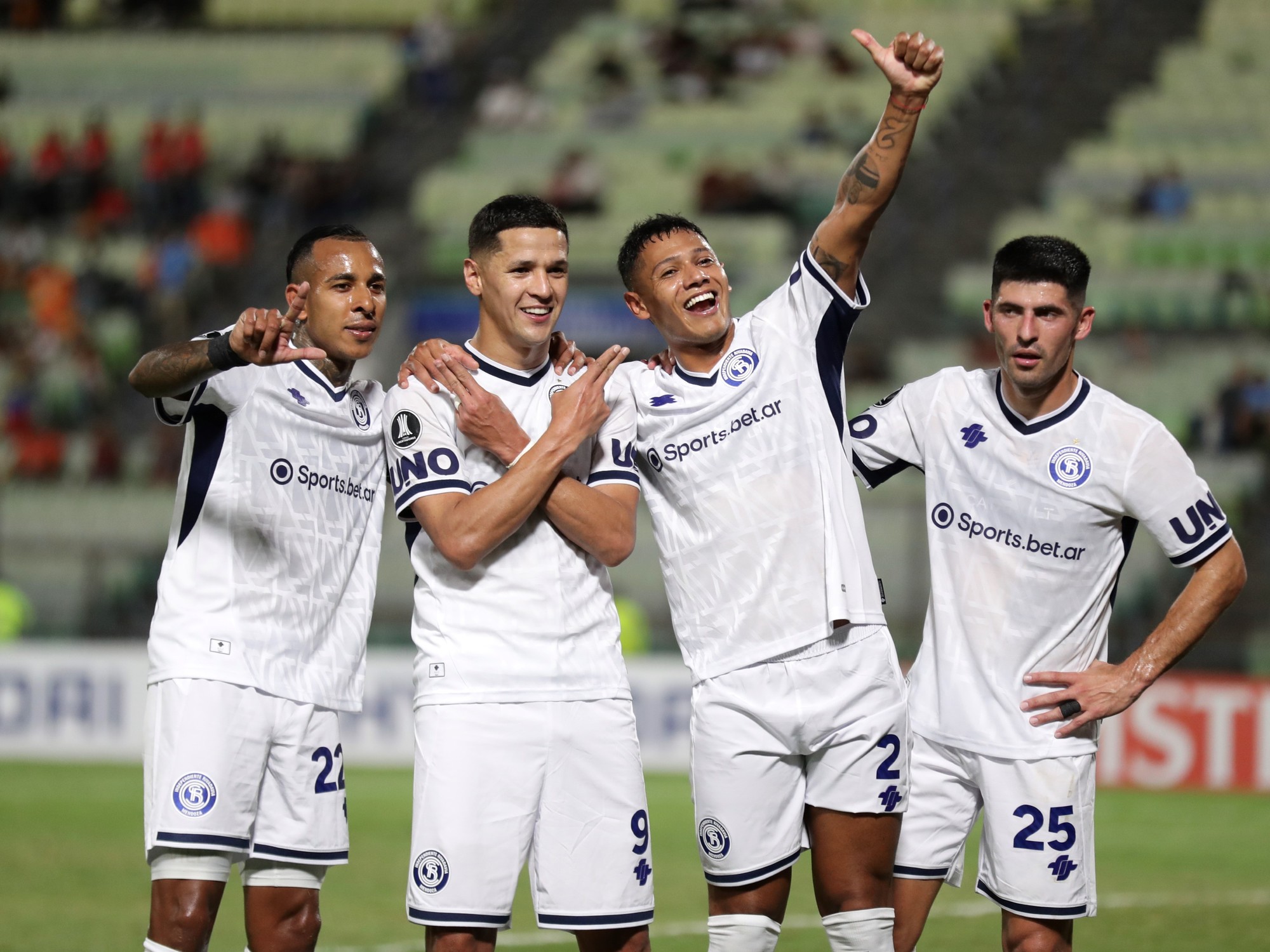 Independiente Rivadavia players celebrating a goal during a Copa Libertadores match, showing team spirit.