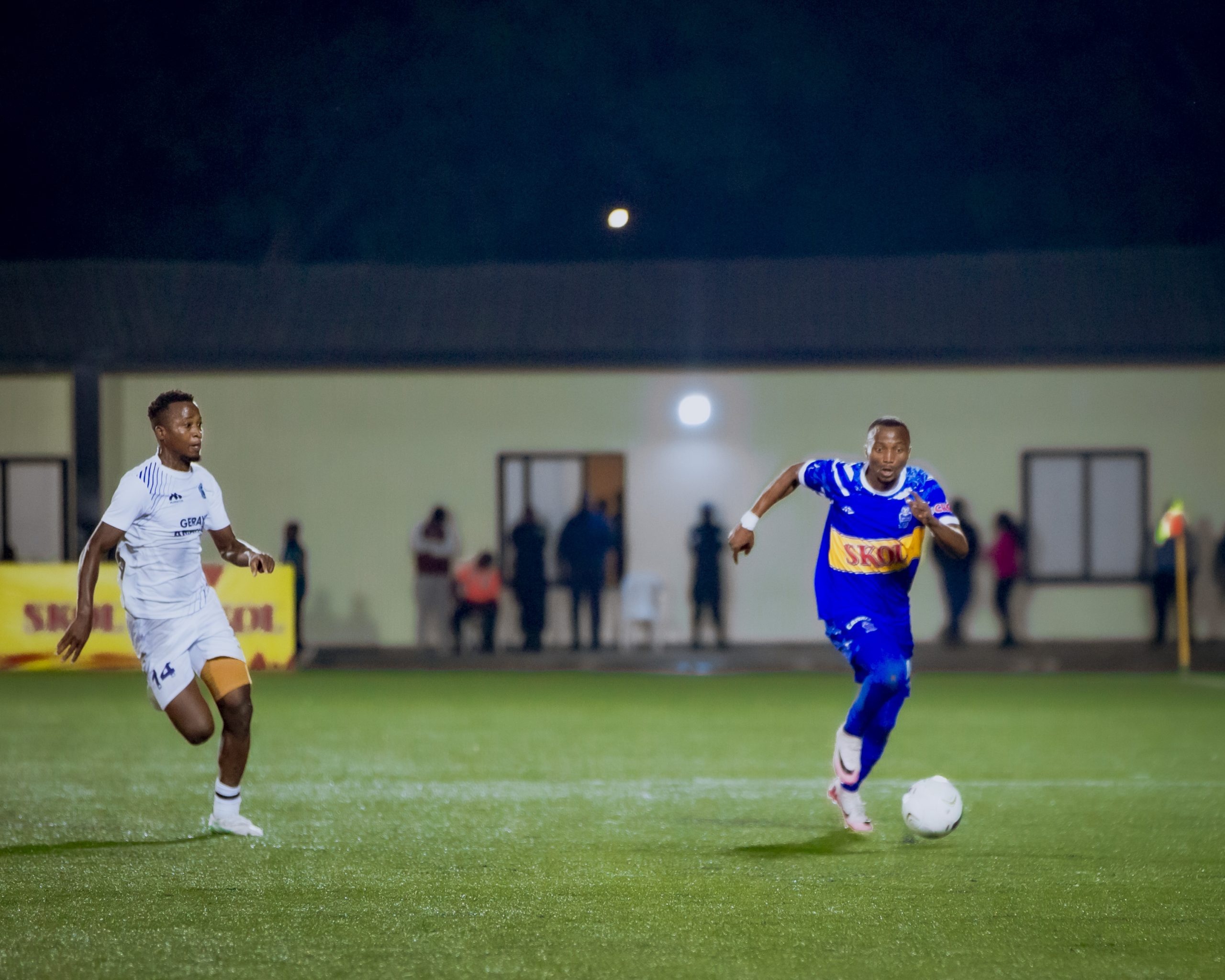 A football player being substituted off the pitch, with a blurred stadium in the background.