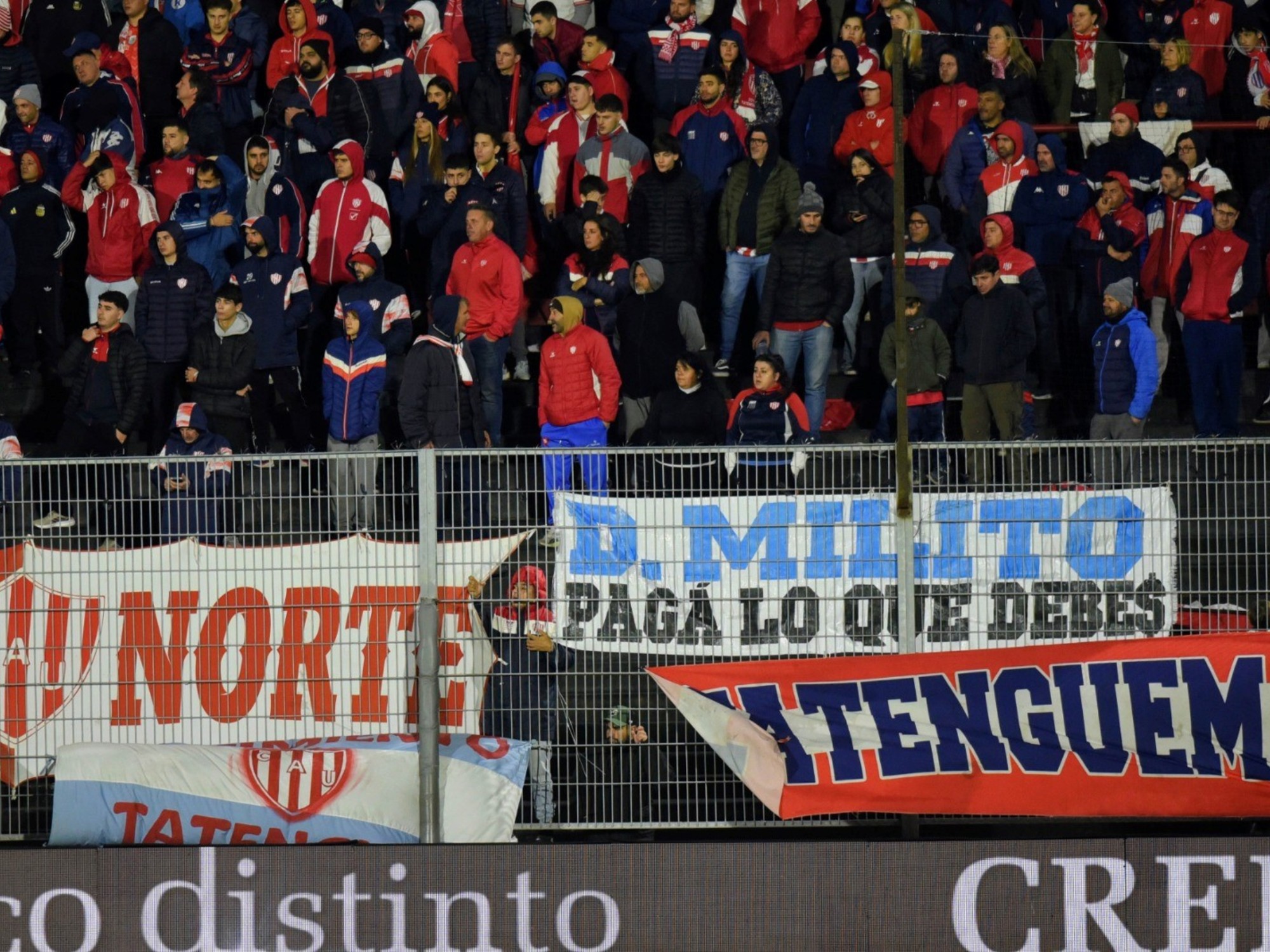 A banner held by football fans in a stadium reads
