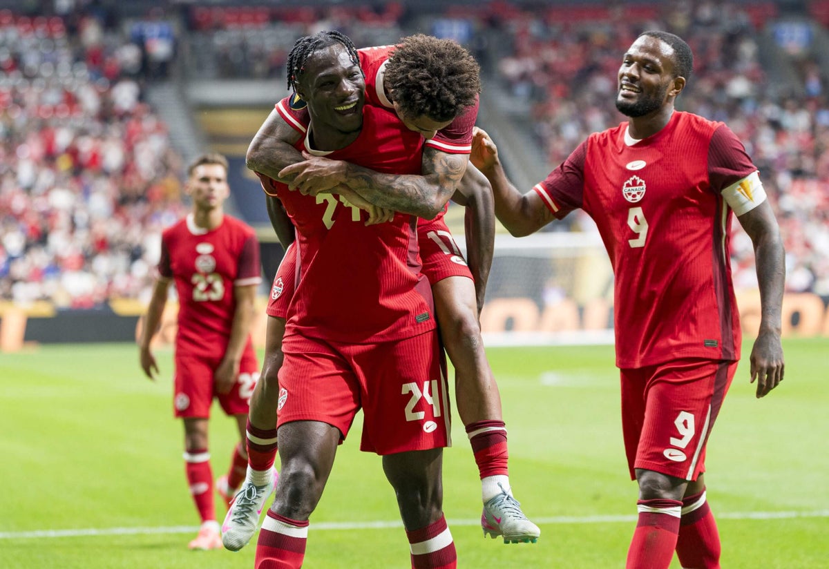 Canada men's national soccer team players celebrating a goal during a match.