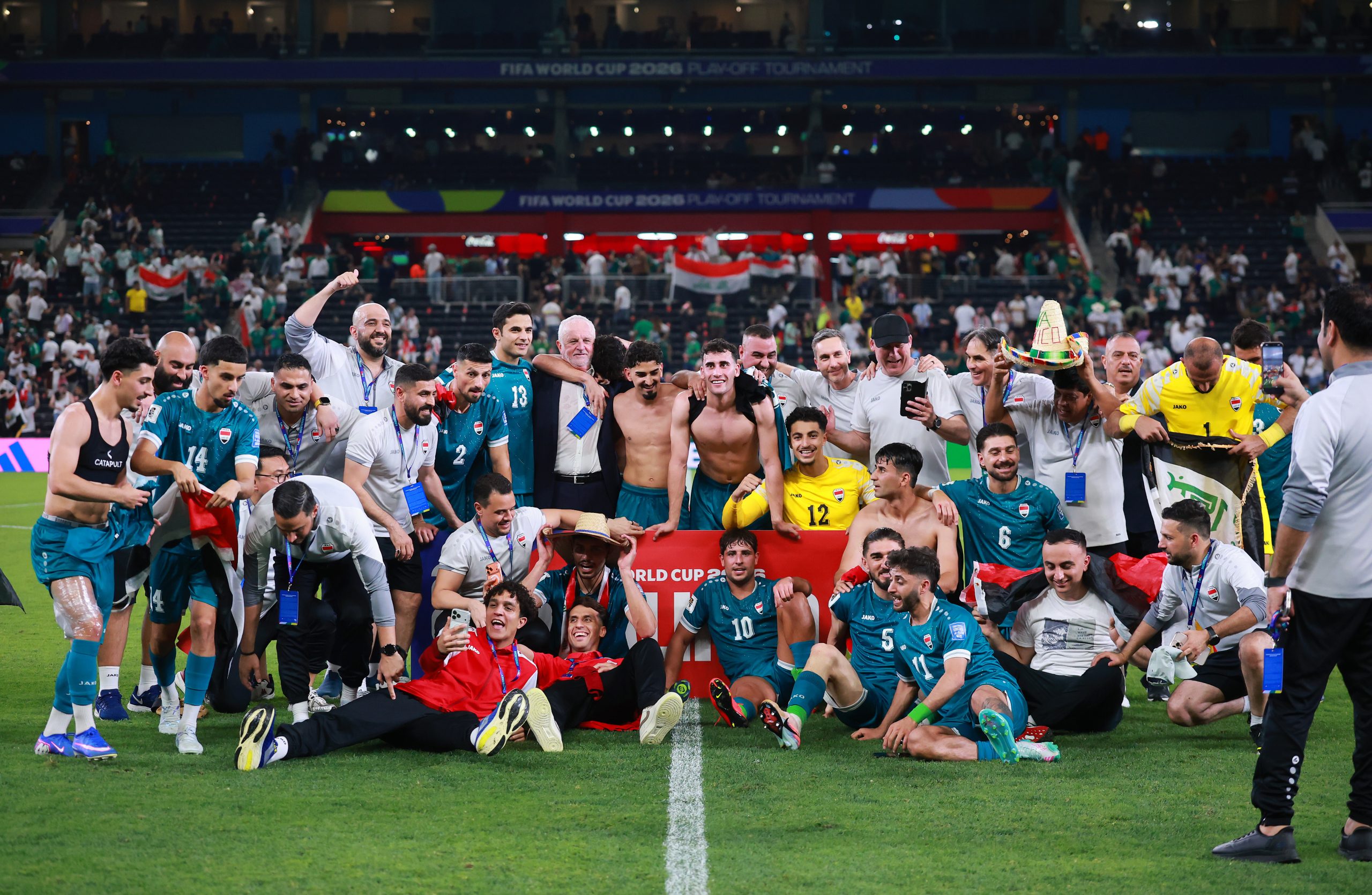 Members of the Iraq national football team celebrating a goal on the field.