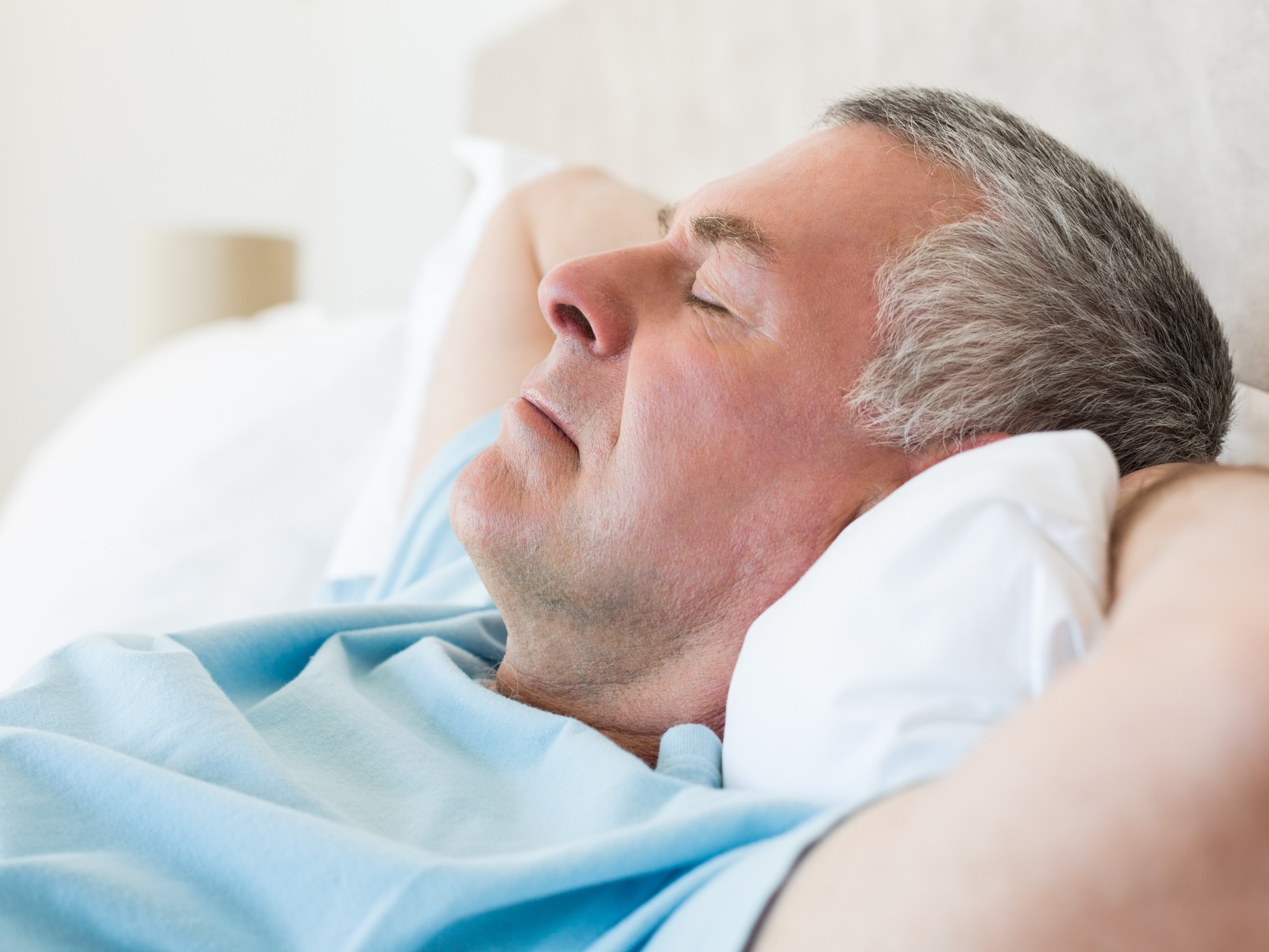 An older person resting on a sofa during the daytime.