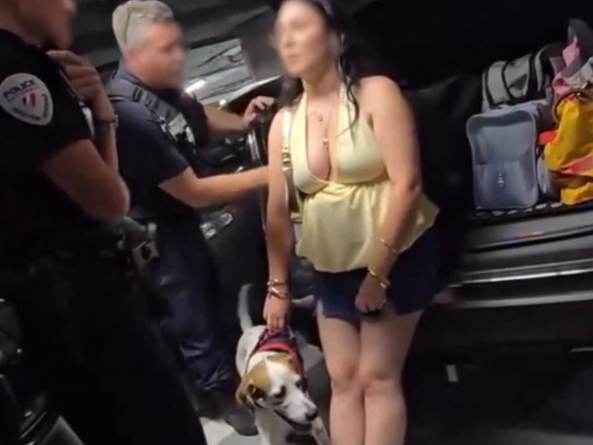 A police officer is seen near a car with its trunk open, where a dog was found, during a heatwave.