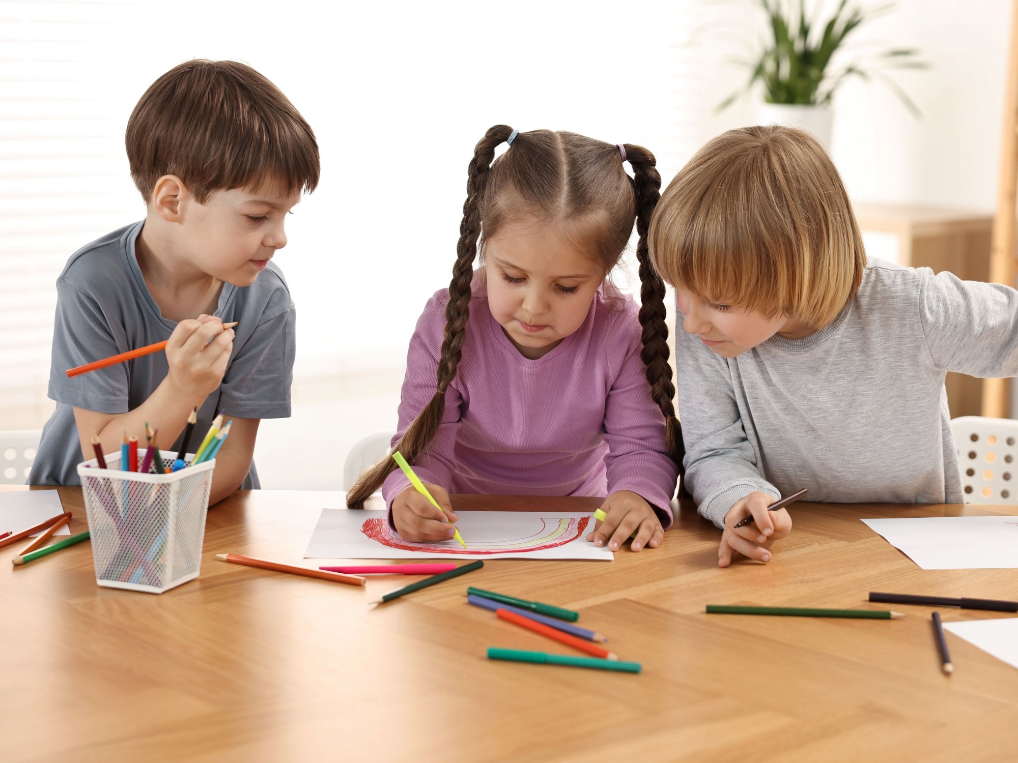 Child concentrating on drawing with colored pencils