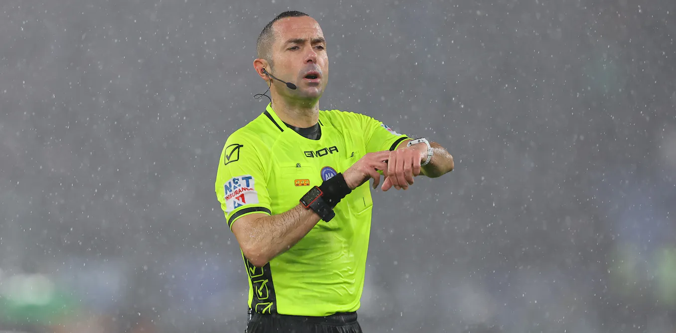 Italian referee Marco Guida signaling to account for time-wasting during a Serie A football match.