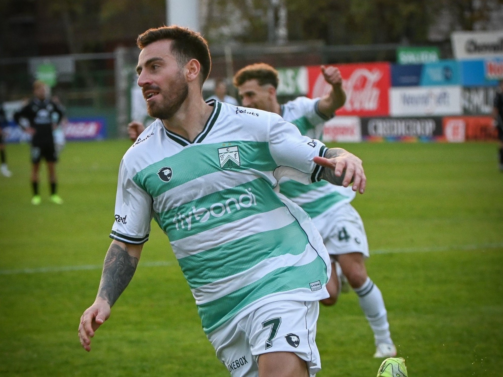 A Ferro player celebrates scoring a goal, with teammates around him.