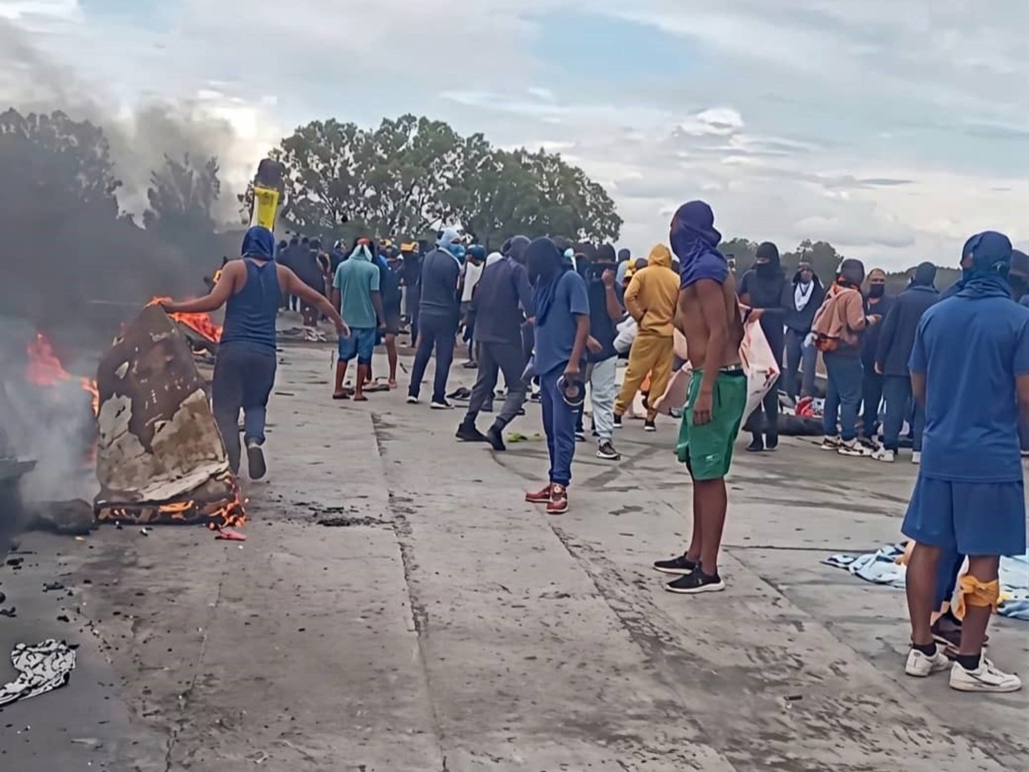 Inmates protesting on the roof of a Venezuelan prison holding banners.