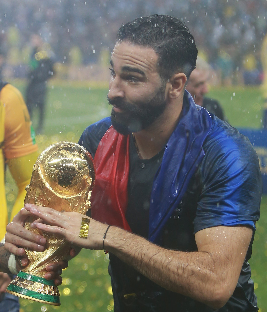 A golden World Cup trophy sits on a football pitch, symbolizing the upcoming tournament.