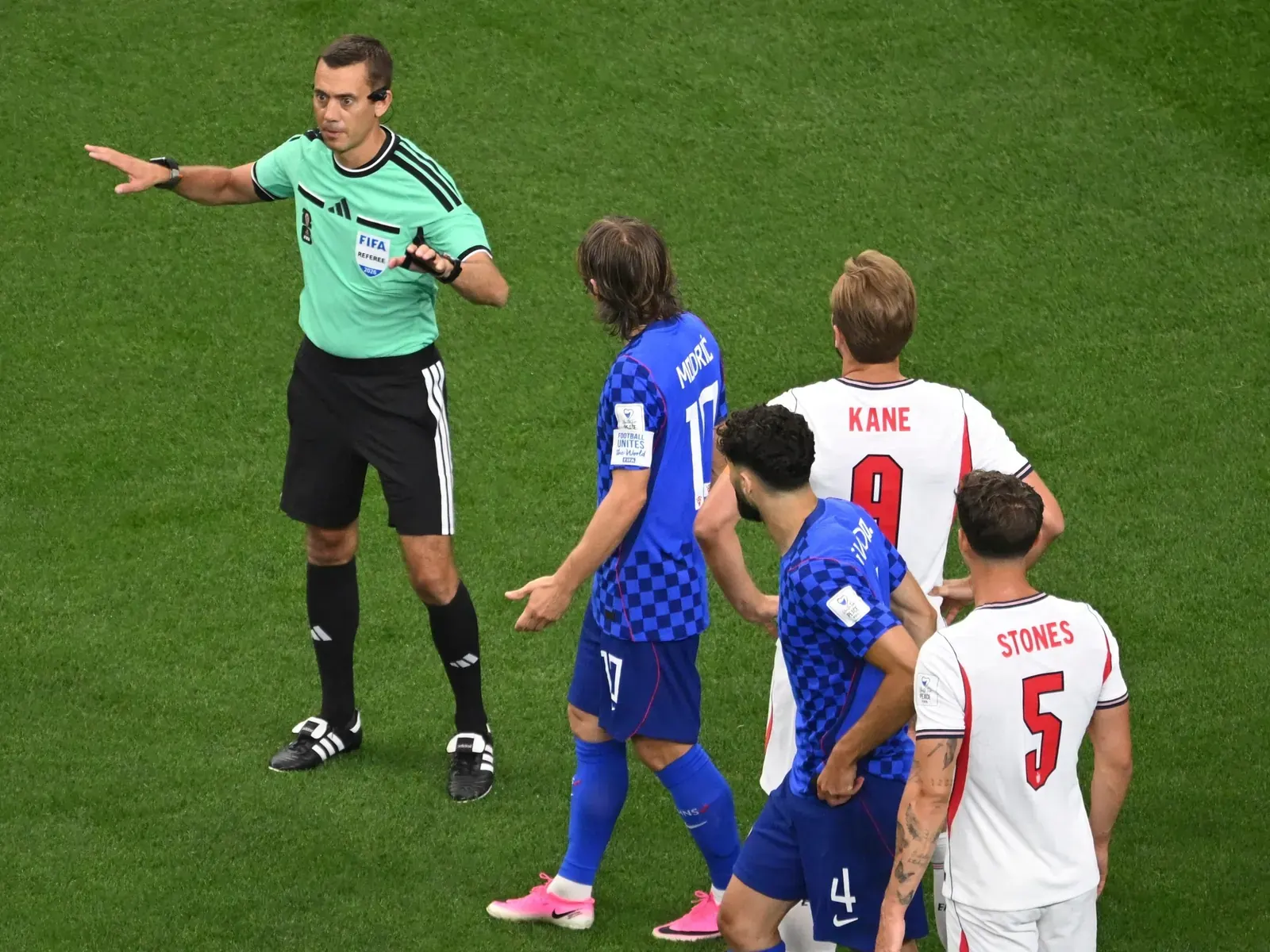 A football referee consulting the Video Assistant Referee (VAR) system during a match.
