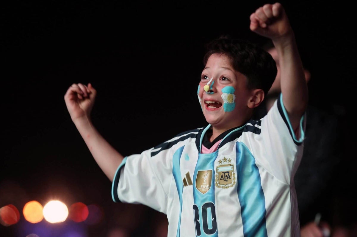 Young football fans cheering enthusiastically at a World Cup match viewing event.