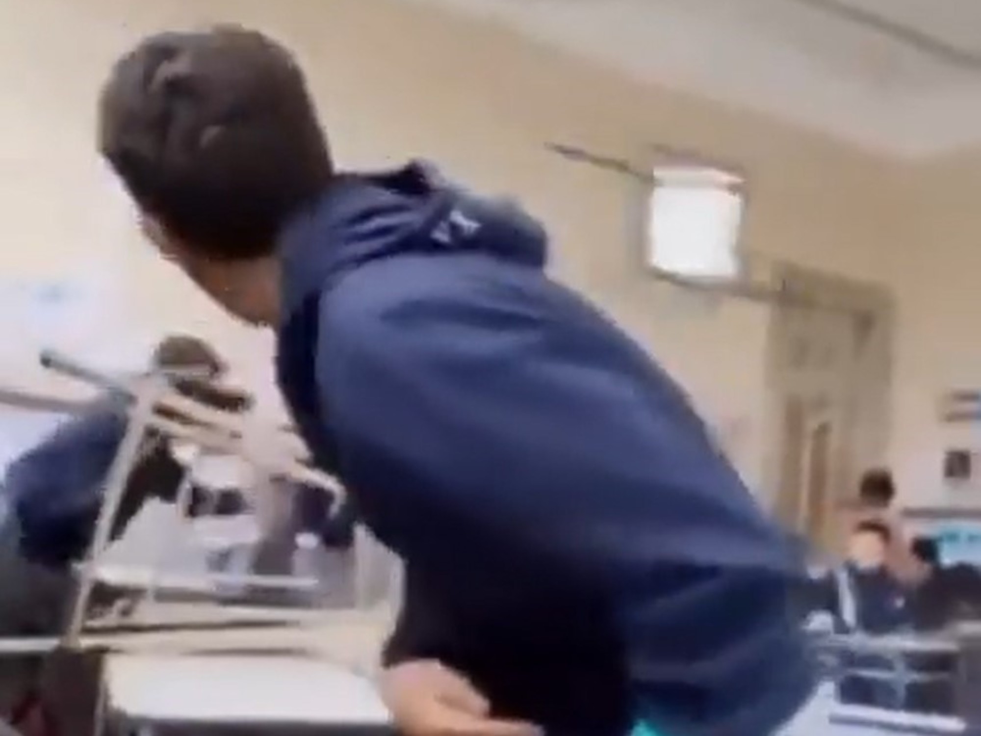 Un joven arrojando una silla en un aula escolar.