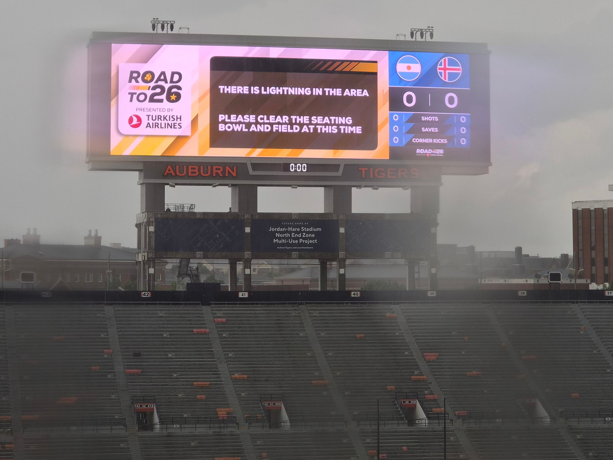 A football stadium under a hot, sunny sky with some clouds.