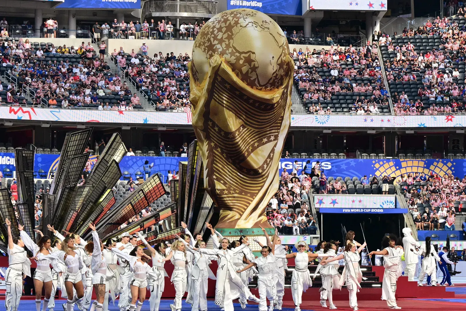 A wide shot of a football stadium during a FIFA World Cup 2026 match, with players on the field.