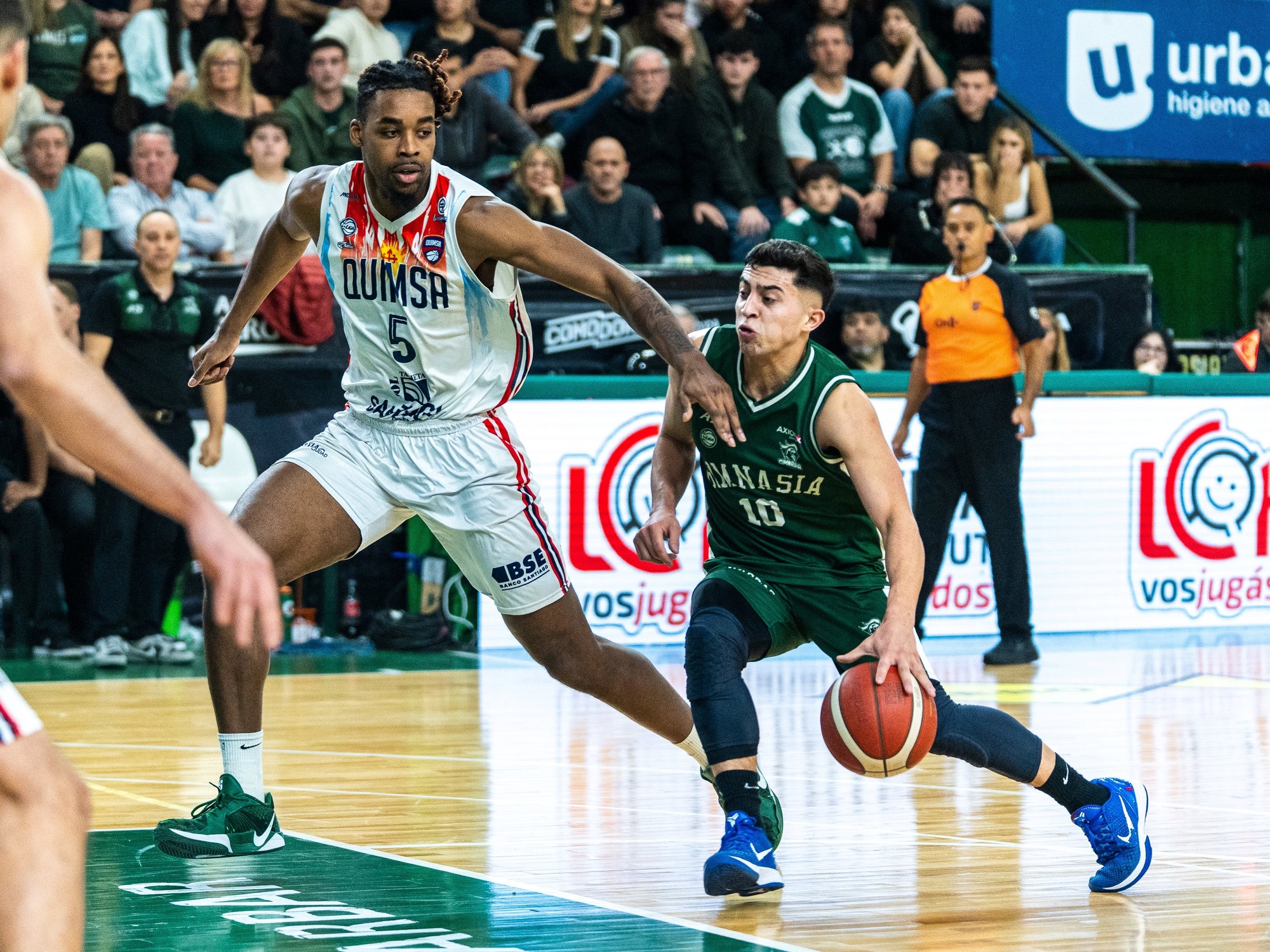 Gimnasia de Comodoro players celebrating a successful play on the court during a basketball game.