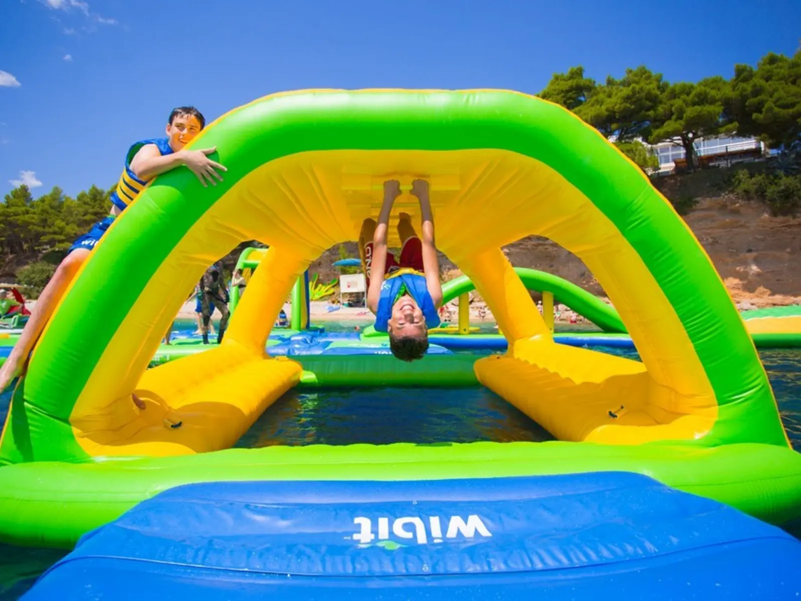 Aerial view of a large inflatable water park on a lake with people enjoying the attractions.
