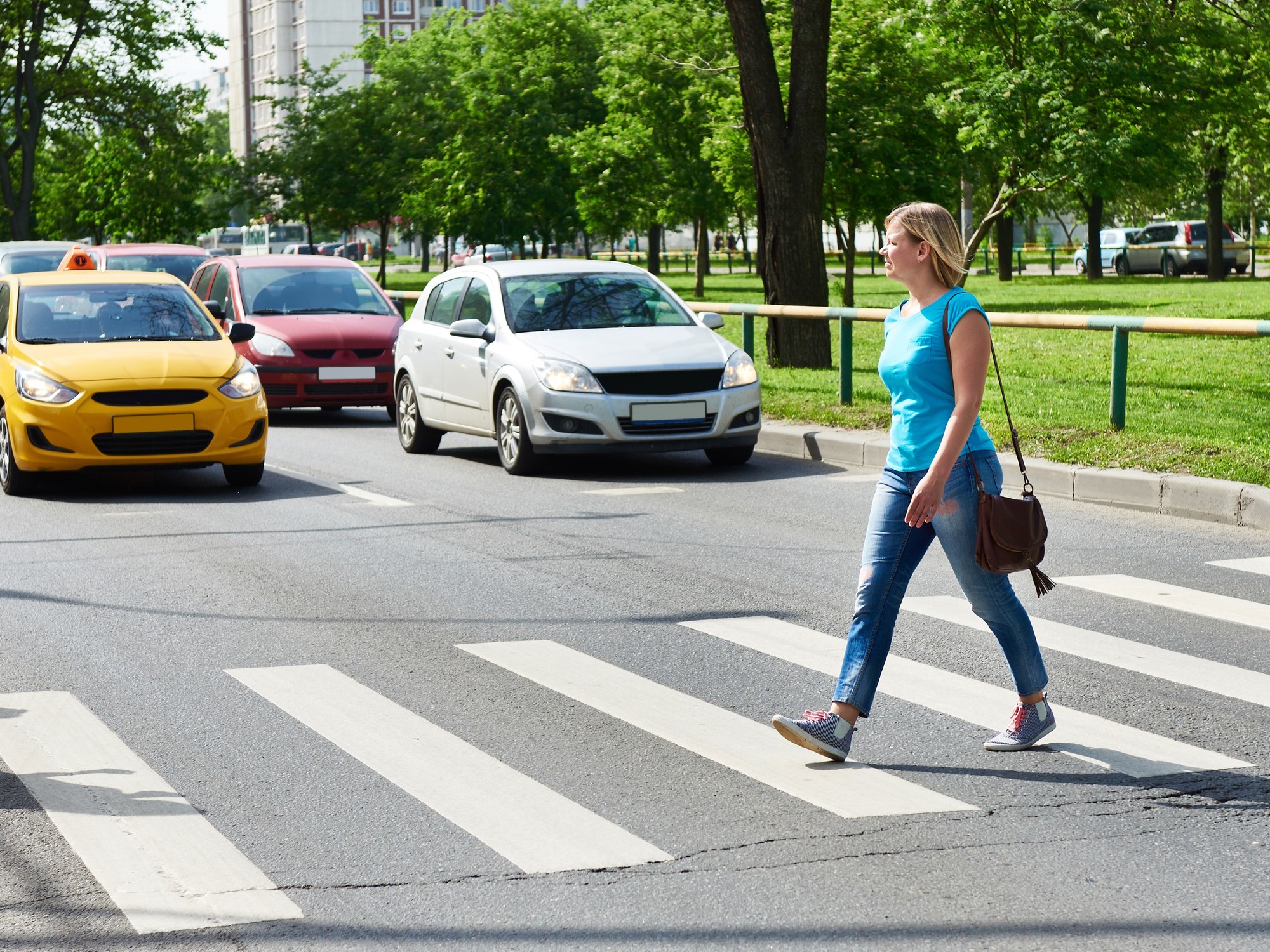 A pedestrian raises their hand to thank a driver who has stopped to let them cross the street.