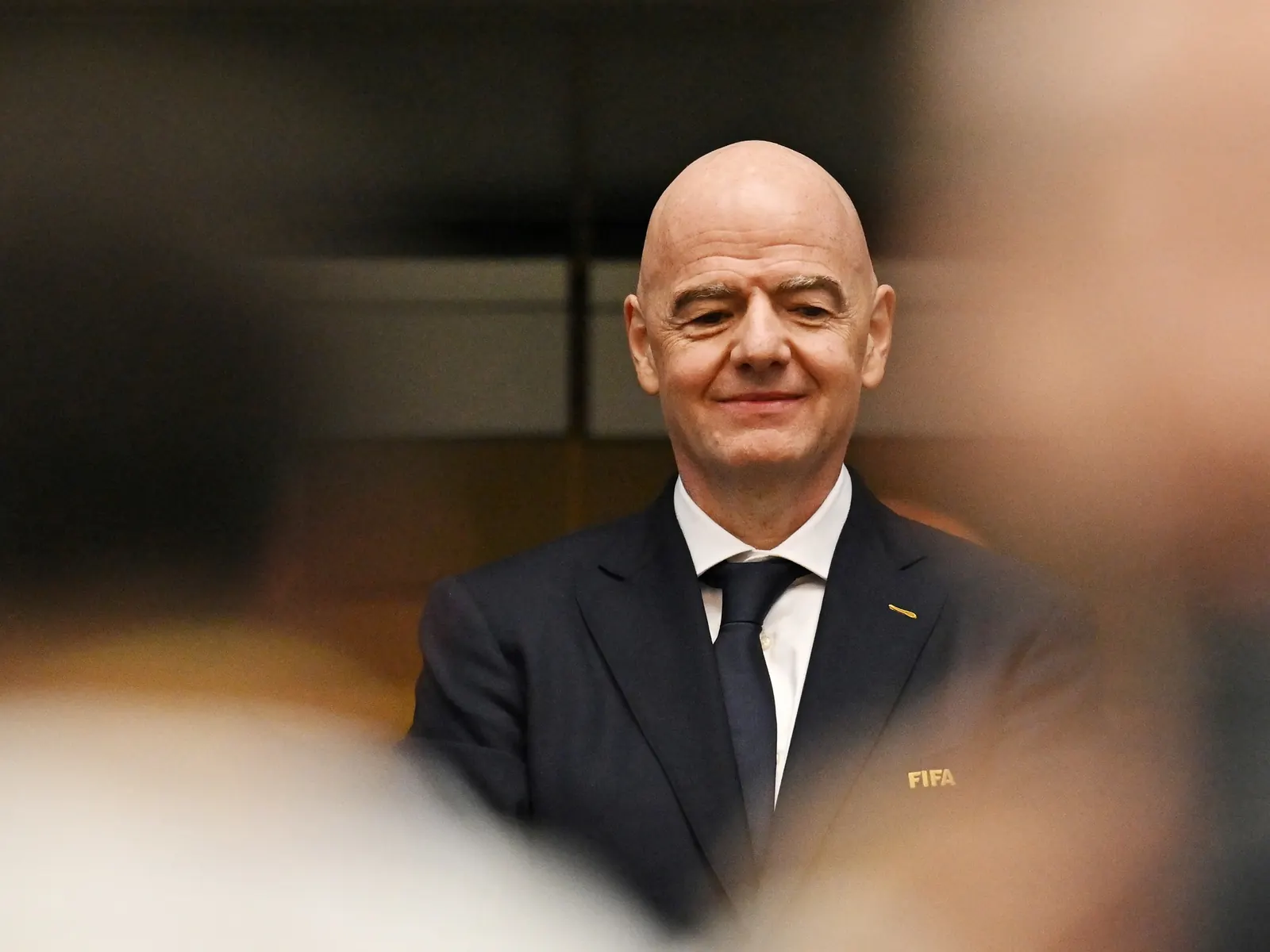 FIFA president Gianni Infantino speaking at a press conference, with FIFA logo and flags in background