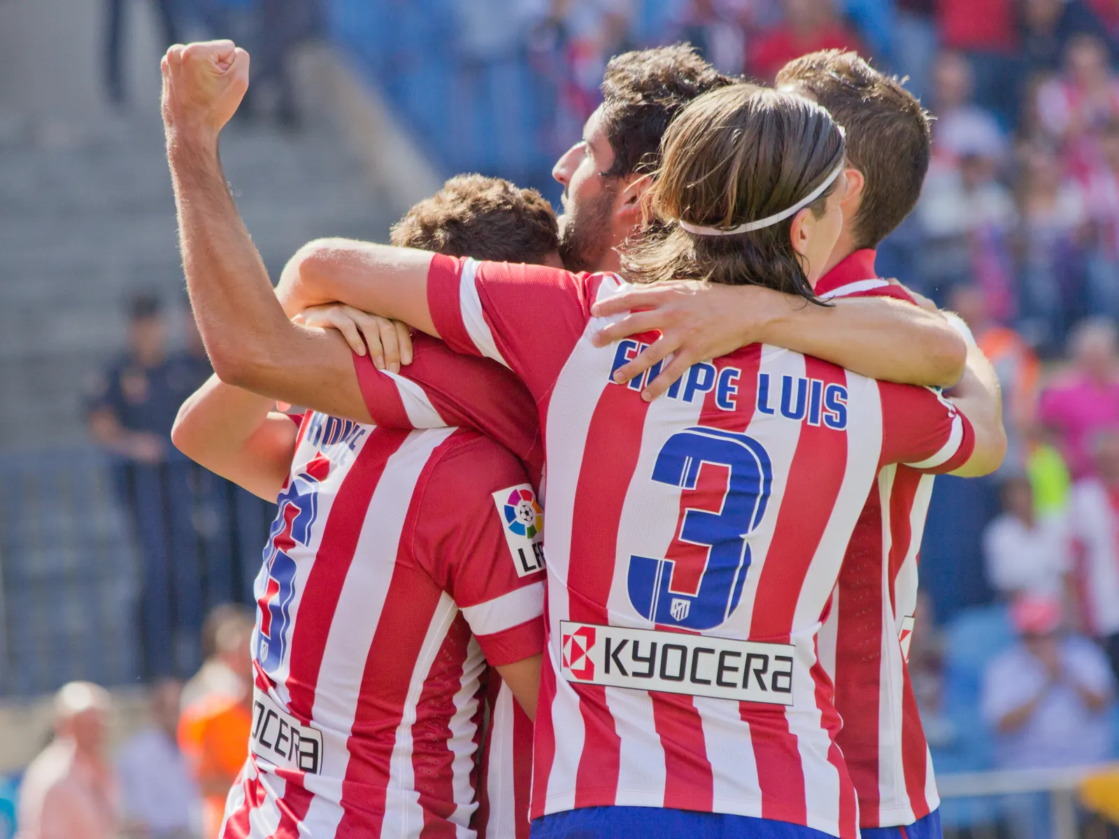 A group of Atlético Madrid players celebrating a significant victory on the football pitch.