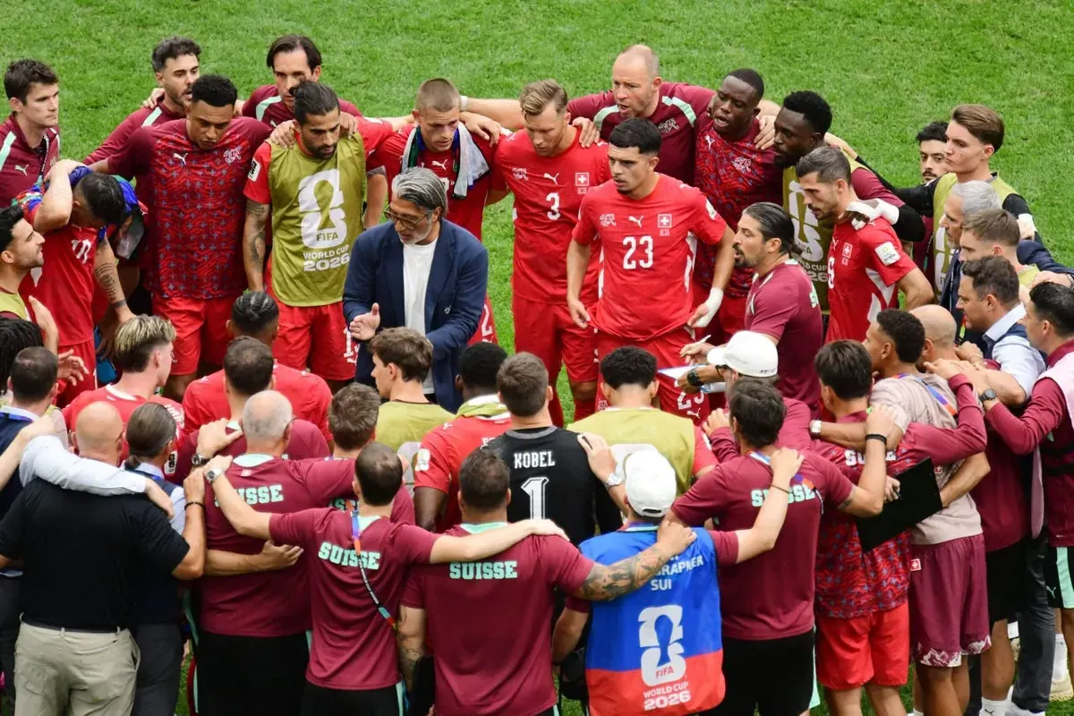 Switzerland players in a focused huddle on the pitch during a penalty shootout at the World Cup.